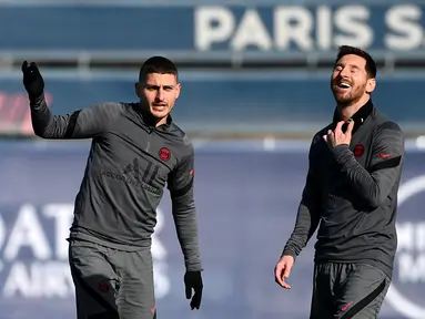 Penyerang PSG Lionel Messi (kanan) tertawa bersama Marco Verratti selama sesi latihan di tempat latihan klub Camp des Loges di Saint-Germain-en-Laye pada 14 Februari 2022. PSG akan menjamu Real Madrid pada leg pertama babak 16 besar Liga Champions, Rabu 16 Februari 2022. (FRANCK FIFE/AFP)