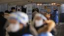 Petugas kesehatan yang mengenakan alat pelindung diri berdiri untuk membantu pengunjung di klinik skrining sementara untuk virus corona dekat Balai Kota Seoul, Seoul, Korea Selatan, Rabu (26/1/2022). (AP Photo/Lee Jin-man)