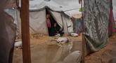 Nanaa Abu Jari memasak di luar tendanya setelah tenda tersebut terendam air hujan di Nuseirat, Jalur Gaza tengah, Jumat, 2 Januari 2026. Hingga awal Januari 2026, wilayah Gaza masih dihantam cuaca ekstrem yang memperparah krisis kemanusiaan di sana. (AP Photo/Abdel Kareem Hana)