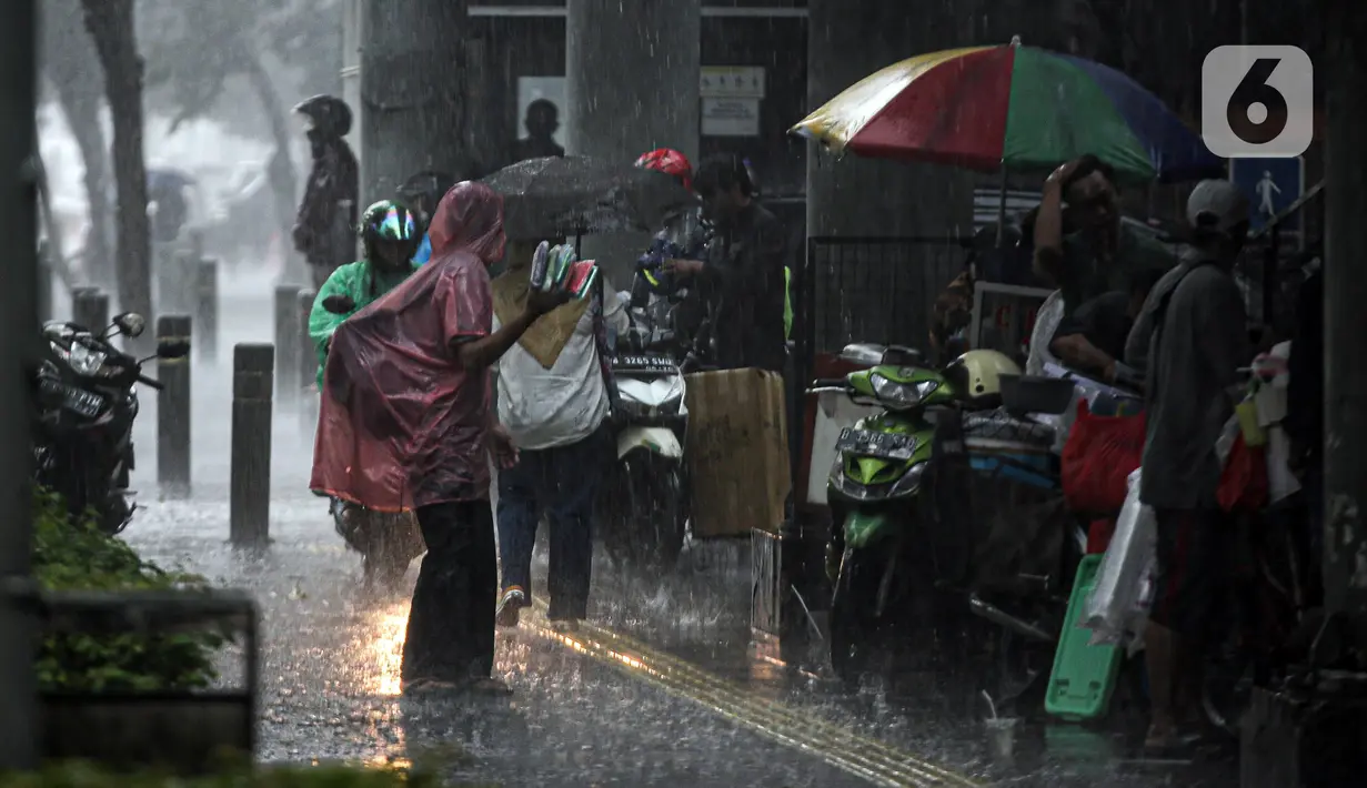 Aktivitas warga saat hujan deras di kawasan Jalan Sudirman, Jakarta, Jumat (9/12/2022). Penjabat Gubernur DKI Jakarta Heru Budi Hartono menyebut pihaknya akan mengkaji penerapan bekerja dari rumah atau work from home (WFH), hal ini berkaitan dengan arahan dari Presiden Joko Widodo atau Jokowi tentang potensi cuaca ekstrem pada penghujung 2022. (Liputan6.com/Faizal Fanani)