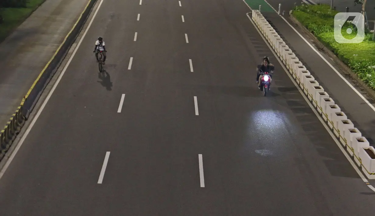 Warga bersepeda di jalan lengang kawasan Sudirman, Jakarta, Rabu (12/5/2021) malam. Polda Metro Jaya memberlakukan crowd free night untuk mencegah kerumunan takbir keliling di malam Idul Fitri 1442 yang berlaku mulai pukul 22:00 malam ini. (Liputan6.com/Herman Zakharia)