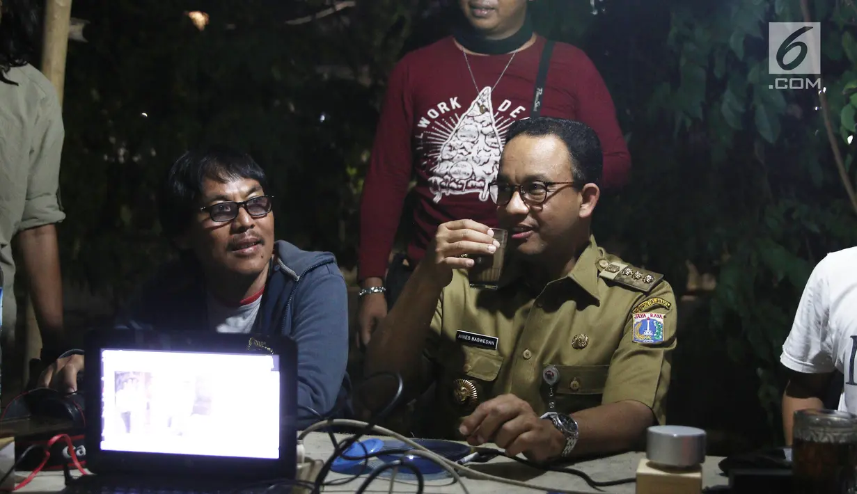 Gubernur DKI Jakarta Anies Baswedan menikmati kopi sambil berbincang dengan Pewarta Foto di Posko Pewarta Foto Bundaran HI, Jakarta, Selasa (13/11). (Liputan6.com/Herman Zakharia)