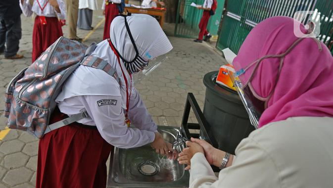 Seorang murid mencuci tangan sebelum memasuki sekolah  SD Negeri 6, Bekasi, Jawa Barat, Selasa (4/8/2020). Pemerintah setempat memberikan izin kepada enam sekolah untuk melakukan uji coba pembelajaran tatap muka selama satu bulan. (Liputan6.com/Herman Zakharia)