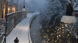 Seorang pejalan kaki berjalan di tengah salju di Milan, Italia (28/12/2020). Hujan salju lebat membuat pohon tumbang yang mengganggu lalu lintas, dengan otoritas lokal mengerahkan puluhan penyumbat salju untuk membersihkan jalan raya utama. (Xinhua/Daniele Mascolo)