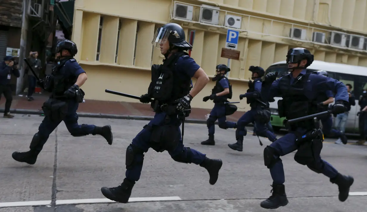 Polisi anti huru-hara saat berusaha membubarkan aksi protes yang berujung bentrok di Mongkok, Hong Kong, Selasa (9/2). Bentrokan dimulai ketika pemerintah daerah mencoba untuk menertibkan PKL yang beroperasi. (REUTERS / Bobby Yip)