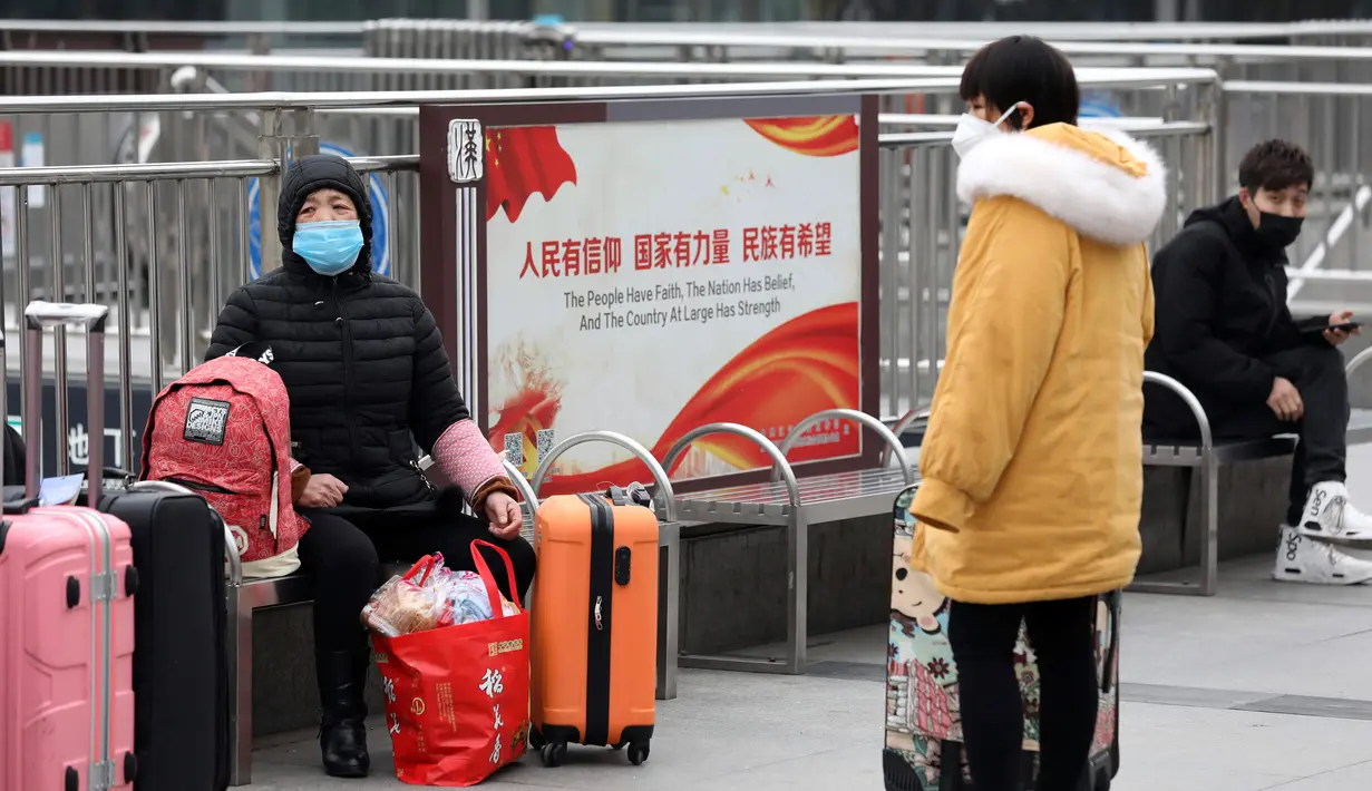 Para pelancong duduk dengan barang-barang mereka di luar Stasiun Kereta Api Hankou yang ditutup di Wuhan, Provinsi Hubei, China, Kamis (23/1/2020). Pemerintah China mengisolasi Kota Wuhan yang berpenduduk sekitar 11 juta jiwa untuk menahan penyebaran virus corona. (Chinatopix via AP)