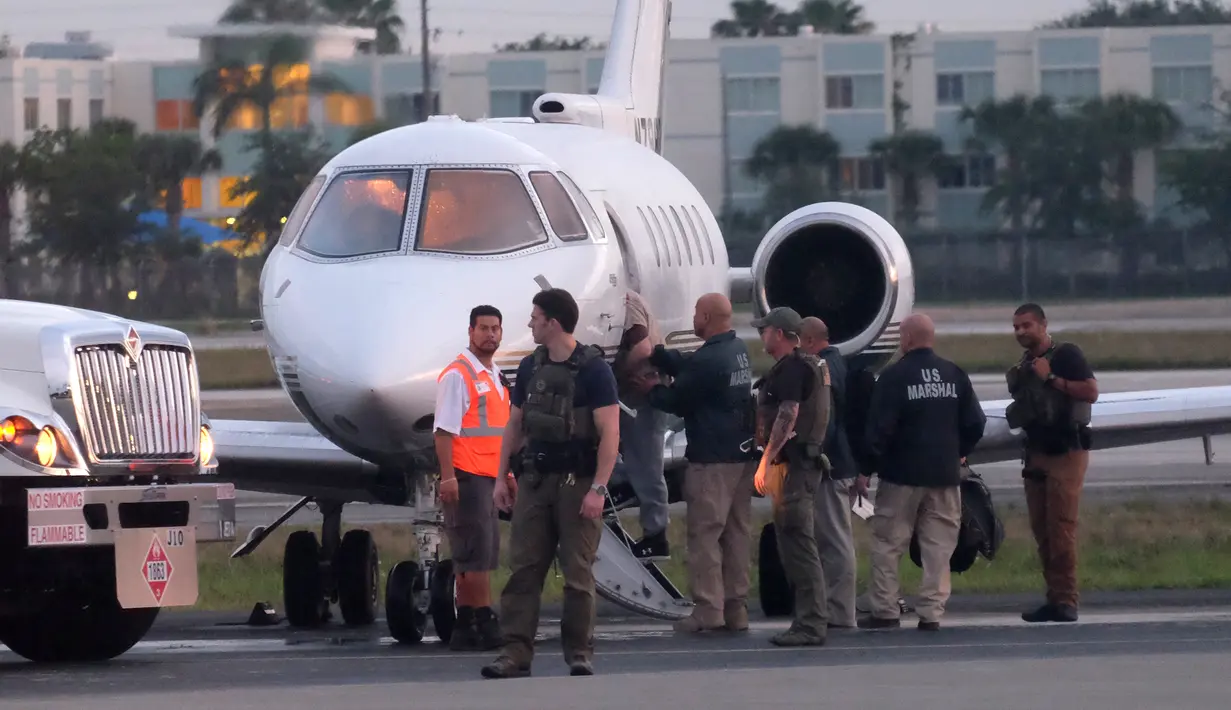 Mantan presiden Panama, Ricardo Martinelli dikawal Marshals AS saat diekstradisi dari Bandara Opa Locka, dekat Miami, Florida, AS, Senin (11/6). Martinelli secara ilegal memata-matai lebih dari 150 orang yang dianggap saingan. (Gaston De Cardenas/AFP)