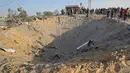 Warga Palestina melihat kawah besar bekas serangan udara Israel di Deir al-Balah di Jalur Gaza selatan, Kamis (14/11/2019). Kementerian Kesehatan Gaza mengatakan, 32 warga Palestina, termasuk anak-anak, telah tewas oleh serangan Israel sejak Selasa (12/11) waktu setempat. (SAID KHATIB/AFP)