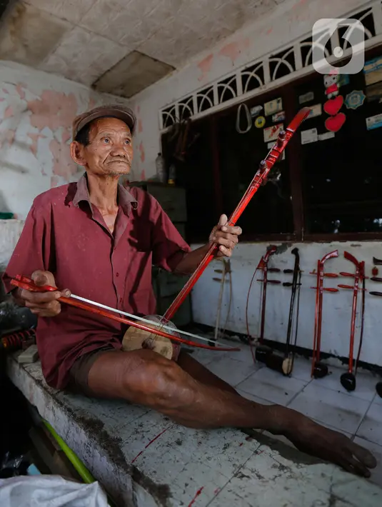 Ghohyong memainkan alat musik Tehyan khas Tionghoa buatannya di Neglasari, Kota Tangerang (5/2/2021). Akibat pandemi Covid-19 membuat pria tua tersebut tidak menerima orderan pembuatan alat musik Tehyan.  (Liputan6.com/Angga Yuniar)