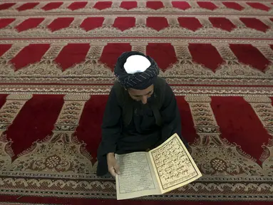Salah satu umat muslim di Kabul, Afghanistan, membaca kitab suci Al Qur'an di hari pertama Ramadan, (29/6/2014). (REUTERS/Omar Sobhani)