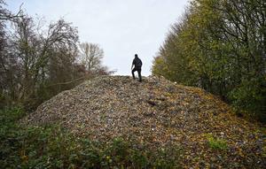 Aktivis lingkungan merekam konten untuk media sosial di tumpukan besar sampah yang dibuang sembarangan, yang ditumpuk di sebuah ladang antara Sungai Cherwell dan Jalan A34 dekat Kidlington, Oxfordshire, di barat London pada 16 November 2025. Gunungan atau tumpukan sampah ilegal berukuran raksasa ditemukan di sebuah ladang di tepi Sungai Cherwell dekat Kidlington, Oxfordshire, Inggris. (Justin TALLIS/AFP)