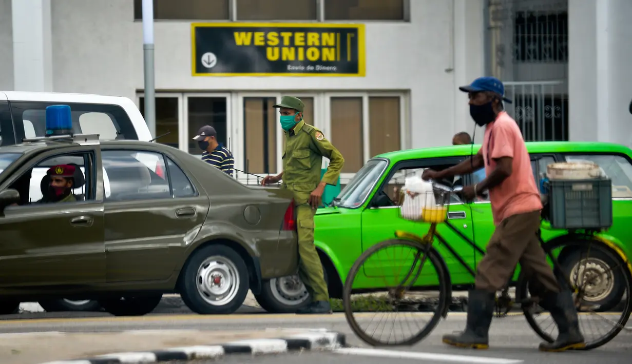 Petugas keamanan terlihat di luar Western Union sebelum penutup kantor di Havana, Kuba, Senin (23/11/2020). Layanan transfer uang terkemuka di dunia itu menutup lebih dari 400 gerainya di Kuba menyusul sanksi ekonomi terbaru yang dikeluarkan Amerika Serikat (AS) terhadap negara itu. (Yamil LAGE/AFP)