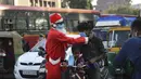 Aksi presiden Angel Foundation dan pekerja sosial, Rufas Christian, yang berpakaian Sinterklas memakaikan masker kepada pengguna jalan di persimpangan lalu lintas di Ahmedabad, India, Kamis (17/12/2020). India sejauh ini telah mencatat hampir 10 juta kasus Covid-19. (SAM PANTHAKY / AFP)