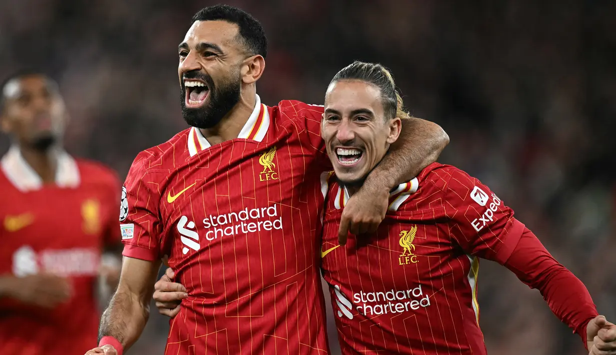 Pemain Liverpool Mohamed Salah (kiri) bersama Kostas Tsimikas merayakan gol pada laga matchday 2 League Phase Liga Champions 2024/2025 melawan Bologna di Anfield Stadium, Inggris pada Rabu 2 Oktober 2024 atau Kamis (3/10/2024) dini hari WIB. (Paul ELLIS/AFP)