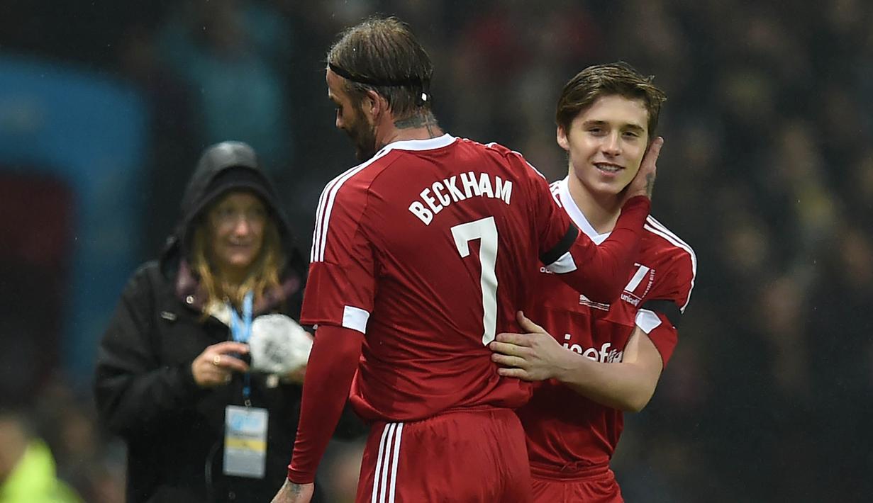 Pemain Great Briitain, David Beckham, digantikan putranya Brooklyn pada laga amal melawan World XI di Old Trafford, Inggris, Sabtu (14/11/2015) dini hari WIB. (AFP Photo/Paul Ellis)