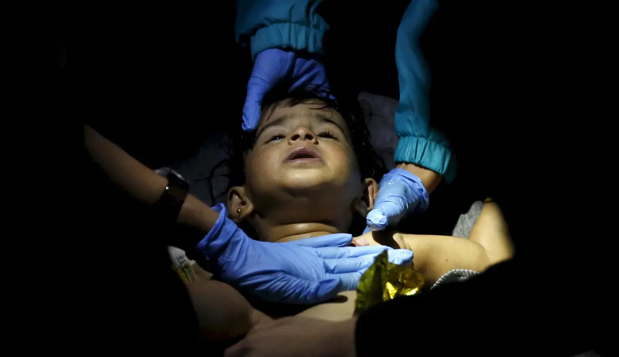 Petugas media saat menangani seorang bocah yang imigran yang tenggelam di laut Aegea, Yunani, 28 Oktober 2015. (REUTERS/Giorgos Moutafis)