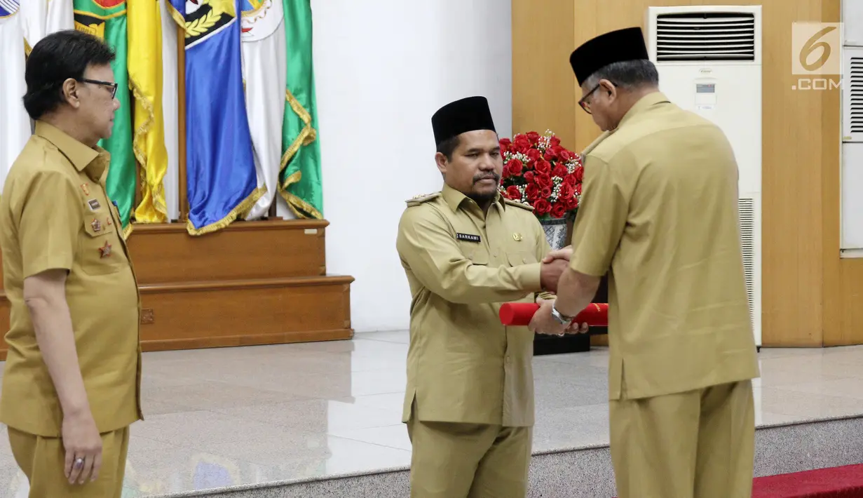 Pelaksana Tugas Gubernur Aceh, Nova Iriansyah menyerahkan surat penugasan Pelaksana Tugas (Plt) Bupati kepada Wakil Bupati Bener Meriah Tgk. H. Sarkawi di Kemendagri Jakarta, Senin (9/7). (Liputan6.com/Herman Zakharia)