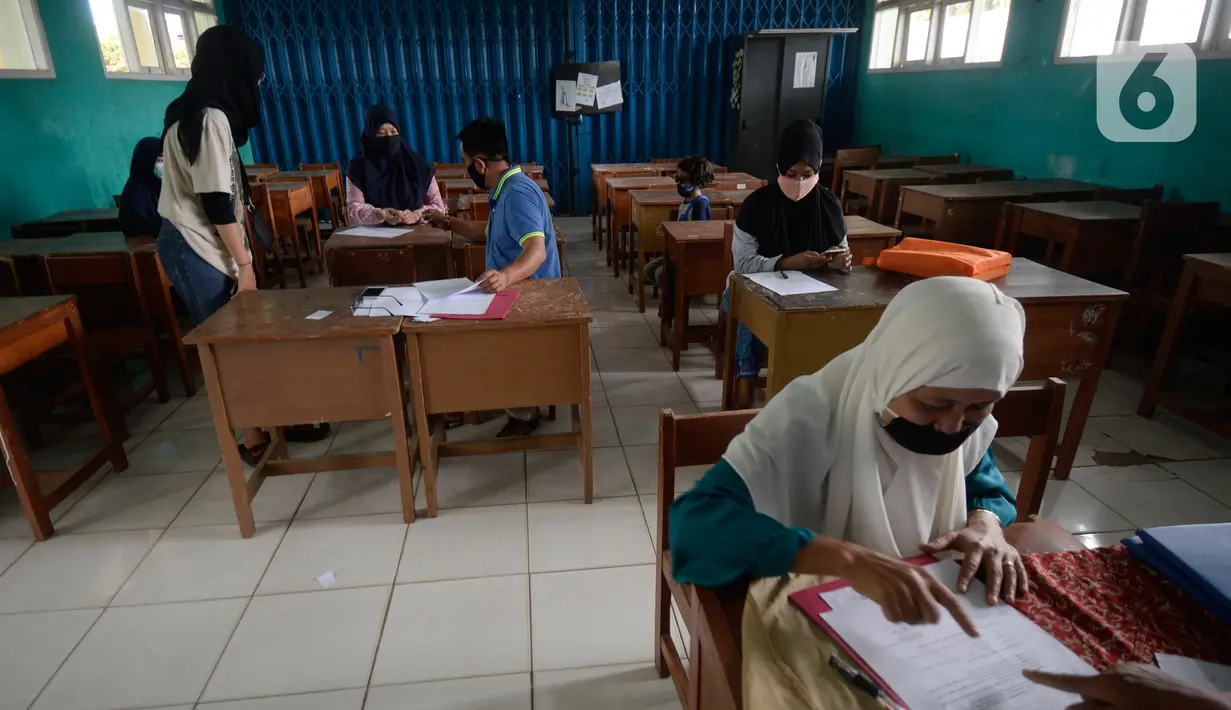 Suasana pembagian raport secara bergilir di SMP Negeri 18 Tangerang Selatan, Banten, Kamis (17/12/2020). Dalam pembagian raport, pihak sekolah menerapkan pola physical distancing atau jaga jarak. (merdeka.com/Dwi Narwoko)