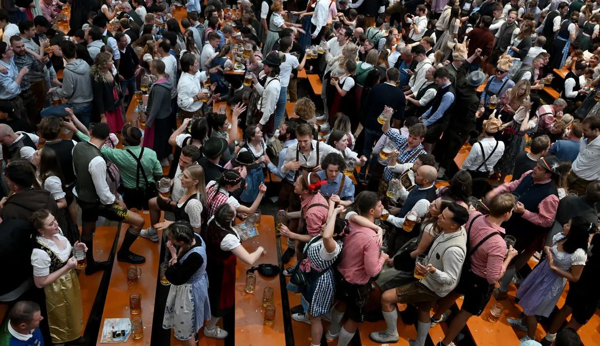 Para pengunjung festival berkumpul dan bersorak di tenda bir selama festival bir Oktoberfest di pasar malam Theresienwiese di Munich, Jerman selatan (20/9/2022). Festival Bir yang terkenal di dunia ini akan berlangsung hingga 3 Oktober 2022 tanpa batasan akses, setelah dua hari terakhir edisi tahun telah dibatalkan karena pandemi coronavirus. (AFP/Christof Stache)