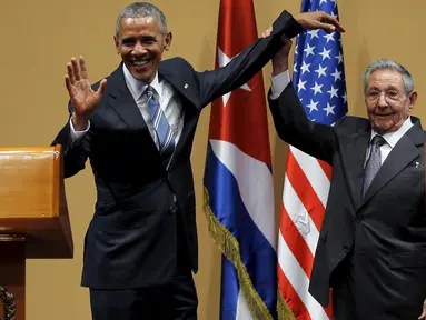 Presiden Kuba Raul Castro mengangkat tangan Presiden AS Barack Obama usai konferensi pers di Istana Revolusi, Havana, Senin (21/3). Obama menjadi presiden pertama AS yang berkunjung ke negara komunis itu sejak 88 tahun terakhir. (REUTERS/Carlos Barria)
