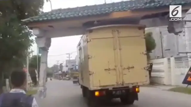 Tanpa sadar sebuah truk box membawa gapura yang ditabraknya.