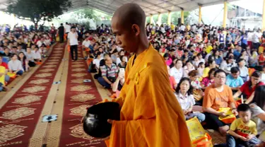 Seorang biksu berjalan di depan umat Buddha yang merayakan Hari Raya Waisak 2562 BE/2018 di Wihara Ekayana Arama, Jakarta Barat, Selasa (29/5). Puja Bakti Massal Waisak 2562 BE diikuti oleh ribuan umat Buddha. (Liputan6.com/JohanTallo)