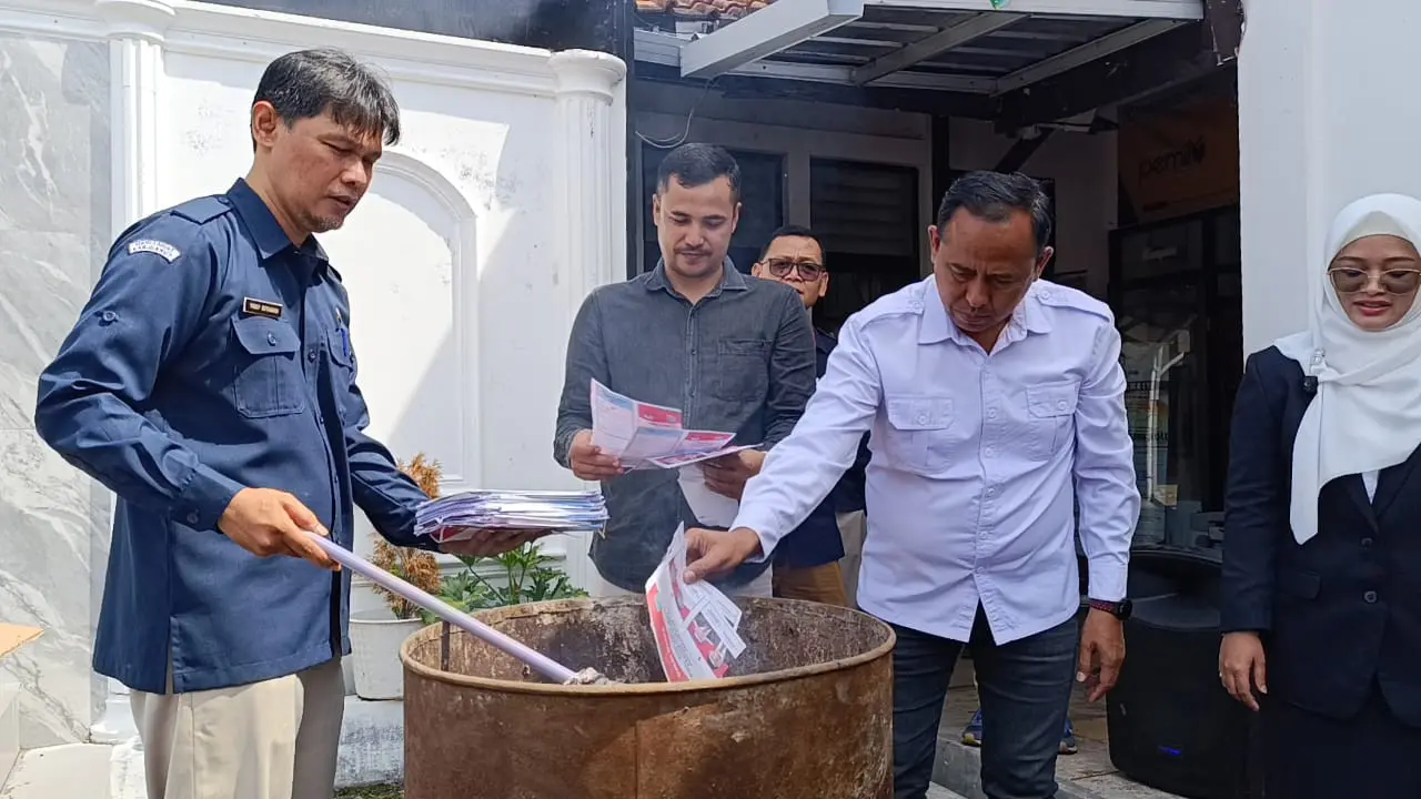 Ketua KPUD Garut Dian Hasanudin bersama Kasatintel Polres Garut saat melaksanakan pemusnahan surat suara rusak di Halaman Kantor KPUD Garut. (Liputan6.com/Jayadi Supriadin)