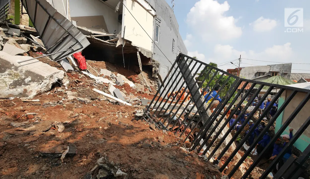 Petugas membersihkan puing longsor di kawasan Perumahan Pesona Kali Sari, Pasar Rebo Jakarta, Selasa (27/11). Intensitas hujan yang tinggi mengakibatkan sebidang tanah di wilayah tersebut longsor. (Liputan6.com/Herman Zakharia)
