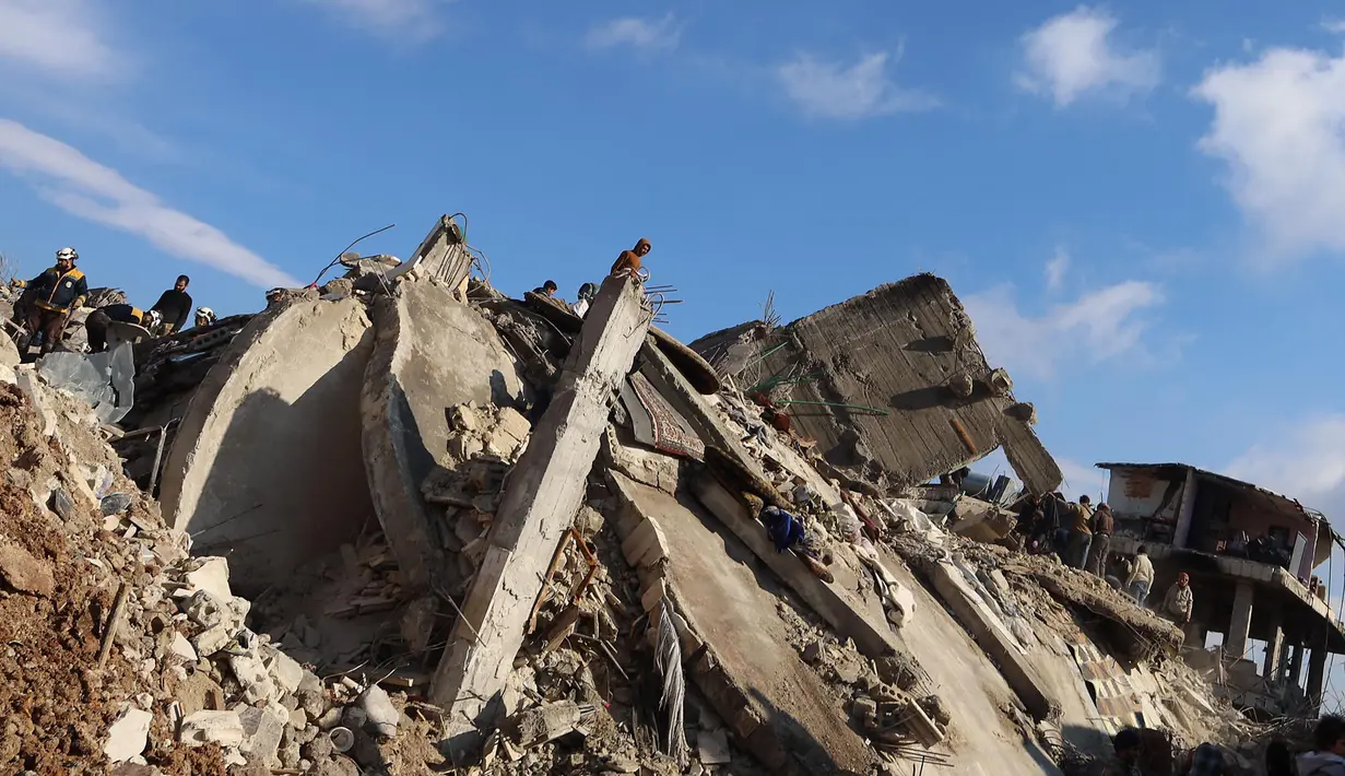 Warga Suriah berkumpul di atas reruntuhan bangunan yang runtuh di kota Jandaris, bagian provinsi Aleppo saat operasi pencarian korban gempa bumi, Selasa (7/2/2023). Berdasar informasi pemerintah setempat dan tim penyelamat, sedikitnya 1.444 orang tewas di seluruh Suriah setelah gempa bumi dahsyat yang berpusat di barat daya Turki. (Mohammed AL-RIFAI/AFP)
