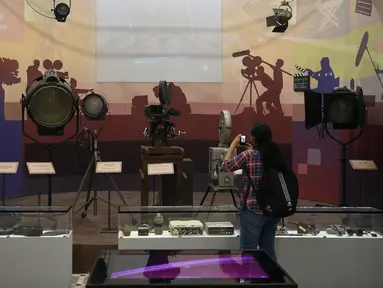 Seorang siswi mengambil gambar kamera tua dan peralatan pencahayaan yang dipajang di Museum Nasional Sinema India (NMIC), Mumbai, India (22/1). NMIC dibangun pemerintah dengan dana US$19,6 juta setara Rp277 miliar. (AFP Photo/Punitparanjpe)