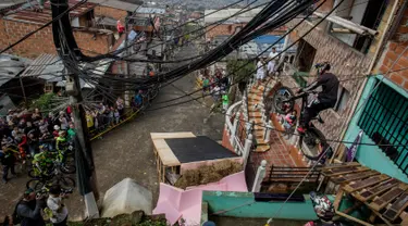 Warga menyaksikan aksi seorang pengendara sepeda saat mengikuti balapan Urban Bike Inder Medellin di gubuk comuna 1 di Medellin, Antioquia department, Kolombia (19/11). (AFP Photo/Joaquin Sarmiento)