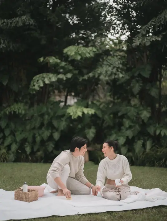 Suasana hangat langsung terasa dari potret yang dibagikan. Duduk berhadapan di atas alas putih di tengah hamparan rumput hijau, Angga dan Shenina tampak larut dalam tawa. Chemistry keduanya terpancar natural, menjadikan sesi maternity ini terasa personal sekaligus stylish. [@sheninacinnamon].