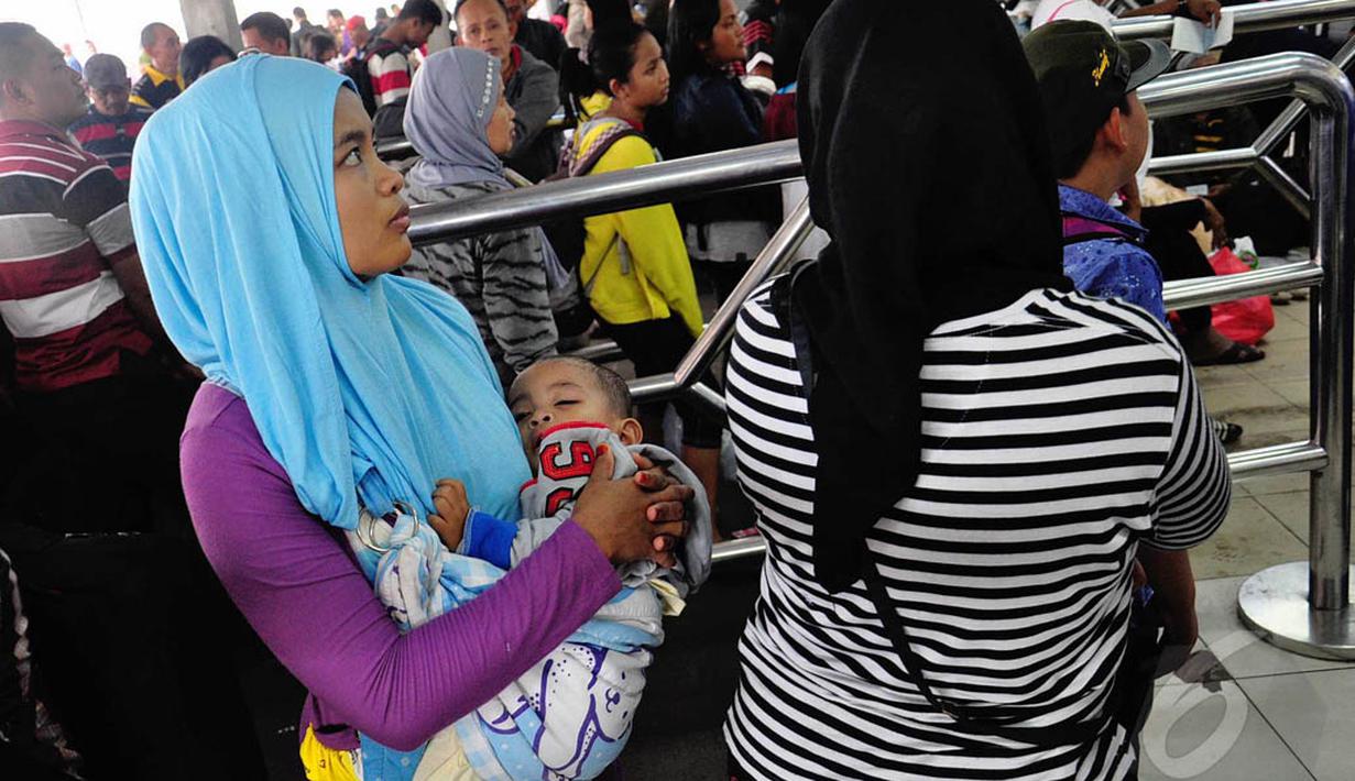 Seorang balita tampak tertidur digendongan ibunya di Stasiun Pasar Senen, Jakarta, Jumat (1/8/14). (Liputan6.com/Faizal Fanani)
