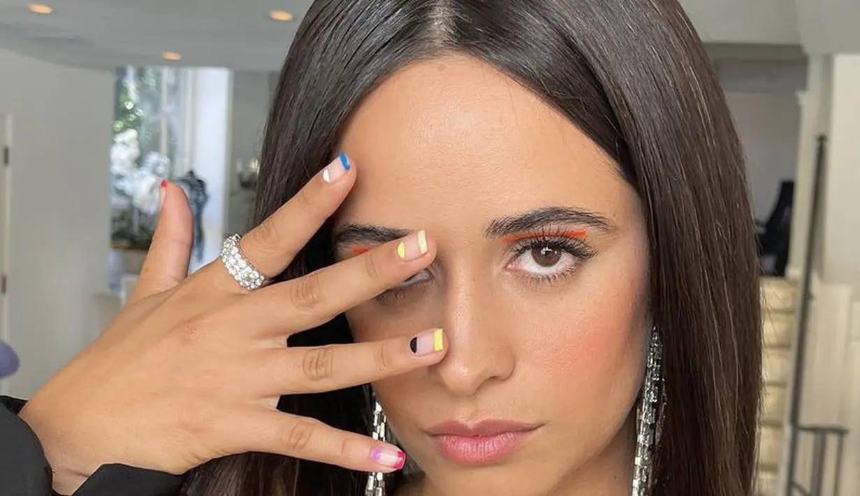 Camila Cabello pun mengenakan graphic eyeliner untuk riasan matanya, ia mengenakan eyeliner satu garis warna coral terang di kelopak matanya. Instagram @camila_cabello