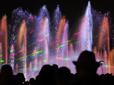 Pengunjung menyaksikan air mancur menari pada awal musim semi di taman Warsawa, Polandia, 1 Mei 2018. Atraksi ini memadukan teknologi pertunjukan lampu laser tiga dimensi, semburan menara api, layar air digital serta pancuran air. (AP/Alik Keplicz)