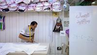 Seorang penjahit memotong kain di tengah tingginya permintaan "dishdasha", pakaian tradisional Kuwait, di toko pakaian adat di Kuwait City pada 23 April 2022. Pakaian tradisional tersebut diburu pembeli, baik tua maupun muda, untuk Idul Fitri yang akan datang. (YASSER AL-ZAYYAT / AFP)