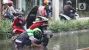 Pengendara memanfaatkan genangan air untuk mencuci kendaraan di Jalan HBR Motik Kemayoran, Jakarta, Selasa (25/2/2020). Hujan yang mengguyur Jakarta sejak Senin (24/2) malam membuat sejumlah kali meluap dan menyebabkan banjir. (Liputan6.com/Helmi Fithriansyah)