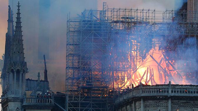 Petugas pemadam kebakaran berusaha memadamkan api dari Gereja Katedral Notre-Dame di kota Paris, Prancis, pada Senin (15/4). Tidak ada laporan korban jiwa dalam kebakaran yang terjadi menjelang perayaan Paskah yang jatuh pada 21 April mendatang. (AP Photo/Thibault Camus)