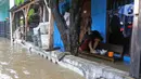 Warga duduk di atas bangku sebuah rumah saat banjir di RW 07, Kelurahan Pekayon, Jakarta Timur, Sabtu (20/2/2021). Banjir di kawasan tersebut terjadi akibat curah hujan yang tinggi. (Liputan6.com/Herman Zakharia)