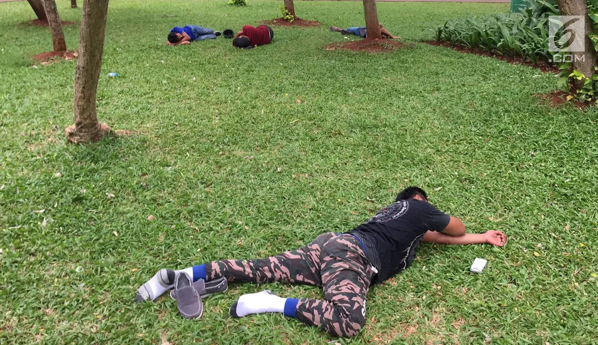 Sejumlah pengunjung tiduran di sekitar Taman Monas, Jakarta, Rabu (17/1). Gubernur Anies Baswedan melalui Kepala Unit Pengelola Kawasan (UPK) Monas mencabut larangan menginjak rumput di kawasan tersebut. (Liputan6.com/Immanuel Antonius)