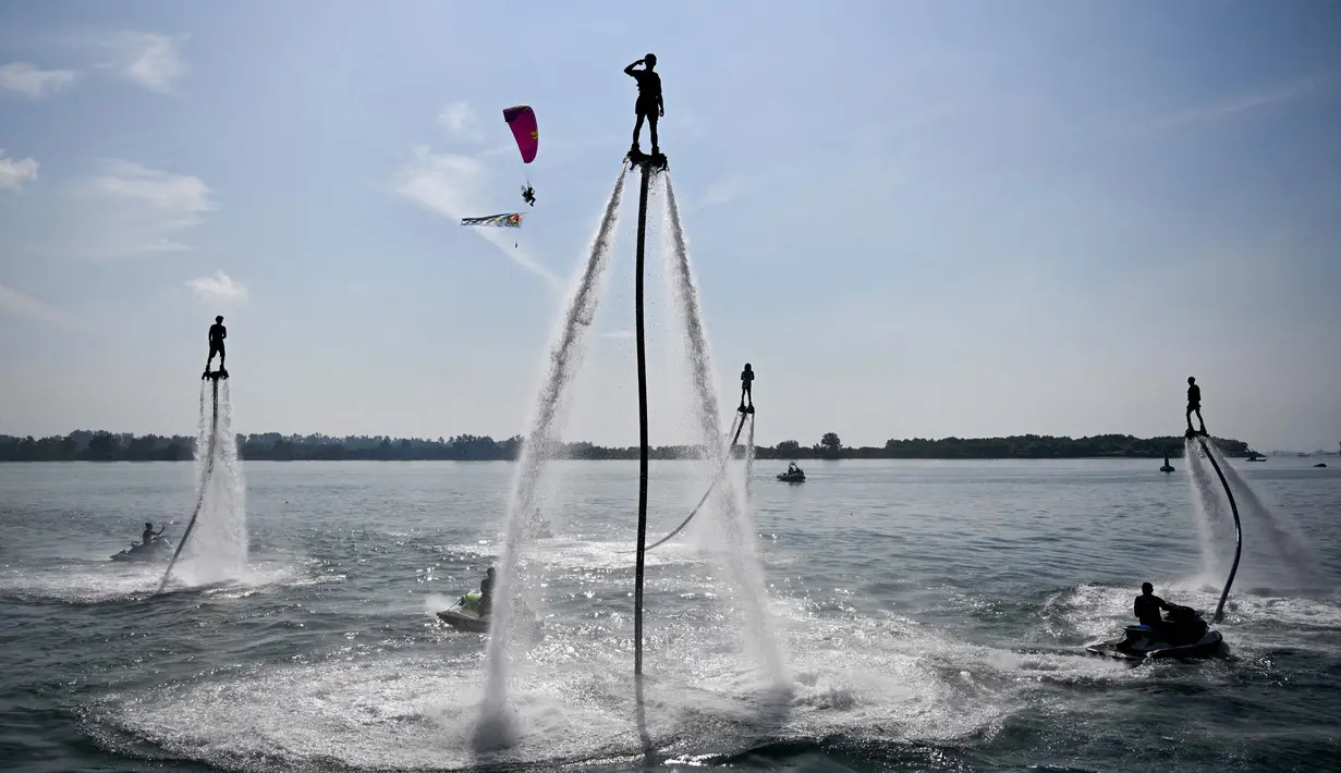 Seorang flyboarder (tengah) memberi hormat saat gladi bersih sehari jelang upacara pembukaan latihan angkatan laut multilateral Komodo 2025 di pelabuhan Benoa, Denpasar, Bali, pada 15 Februari 2025. (SONNY TUMBELAKA/AFP)