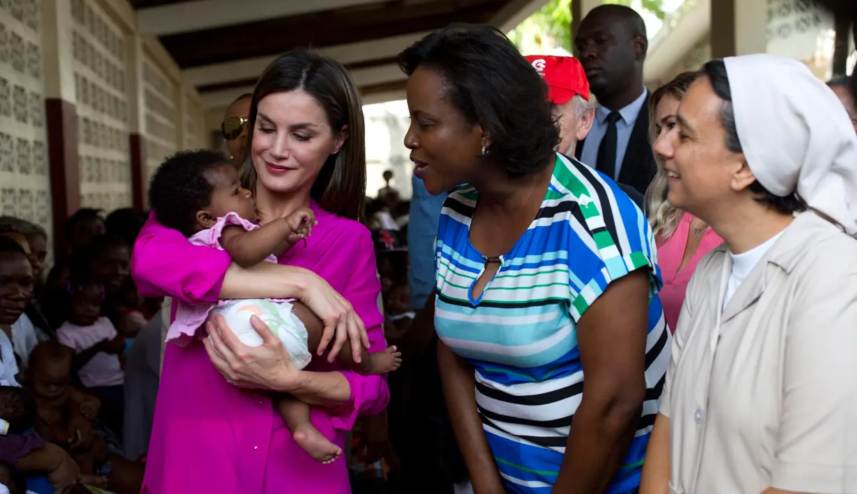 Ratu Spanyol Letizia menggendong seorang bayi perempuan dalam kunjungannya ke rumah sakit di daerah kumuh Soleil, Haiti, 23 Mei 2018. Ini merupakan kunjungan pertama Ratu Letizia ke negara termiskin di benua Amerika tersebut. (AP/Dieu Nalio Chery)