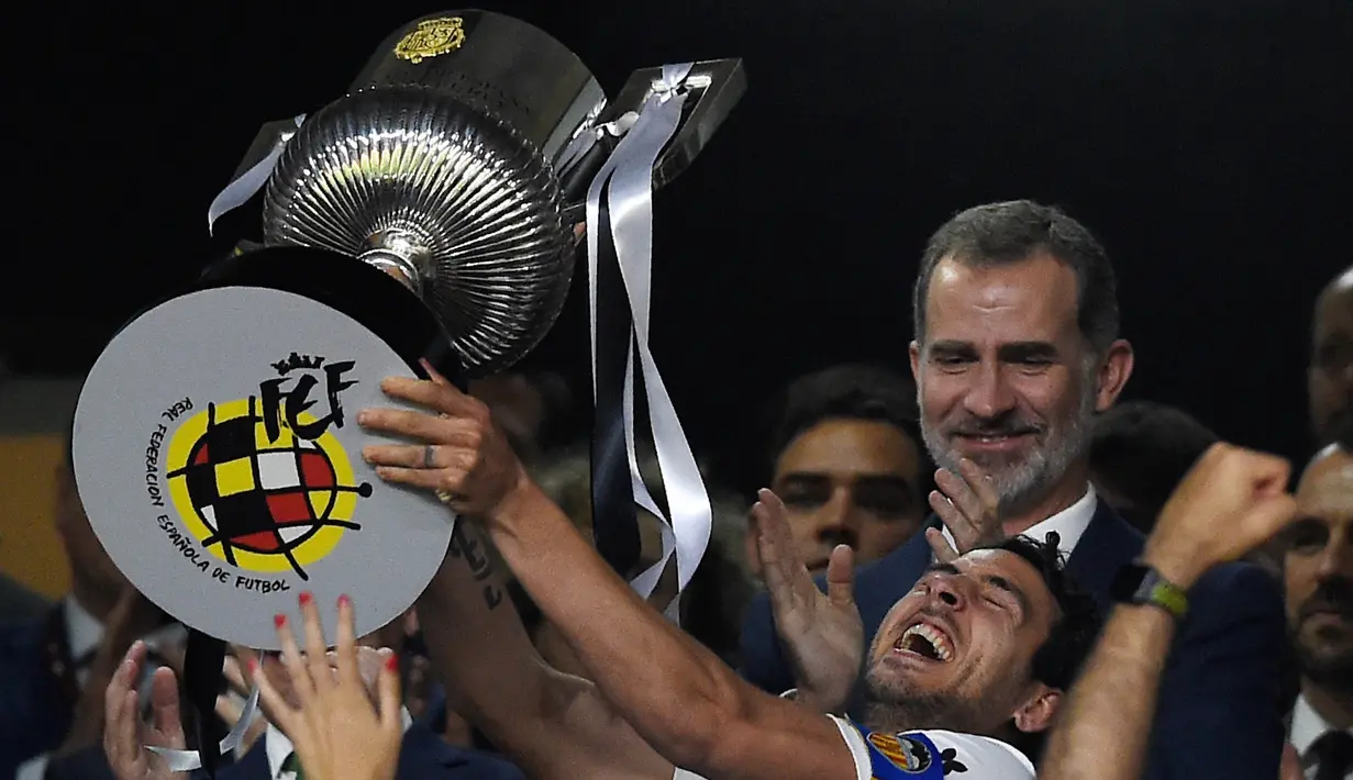 Kapten Valencia, Daniel Parejo, mengangkat trofi Copa del Rey usai mengalahkan Barcelona pada laga Copa del Rey di Stadion Benito Villamarin, Sevilla, Sabtu (25/5). Barcelona kalah 1-2 dari Valencia. (AFP/Pau Barrena)