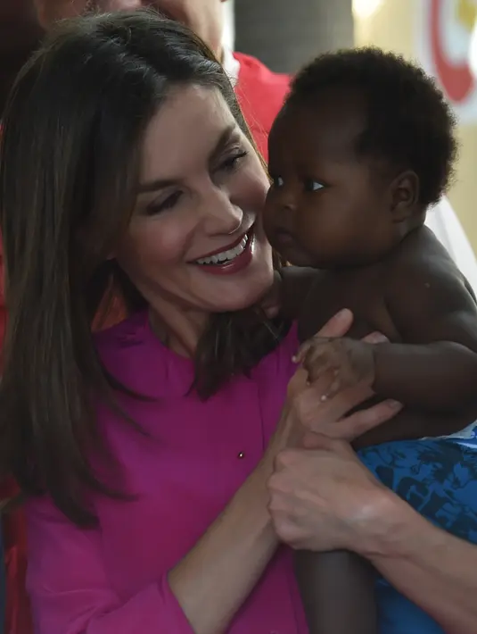 Ratu Spanyol Letizia menggendong seorang bayi dalam pelukannya saat berkunjung ke rumah sakit di daerah kumuh Soleil, Haiti, 23 Mei 2018. Ini merupakan kunjungan pertama Ratu Letizia ke negara termiskin di benua Amerika tersebut. (HECTOR RETAMAL/AFP)