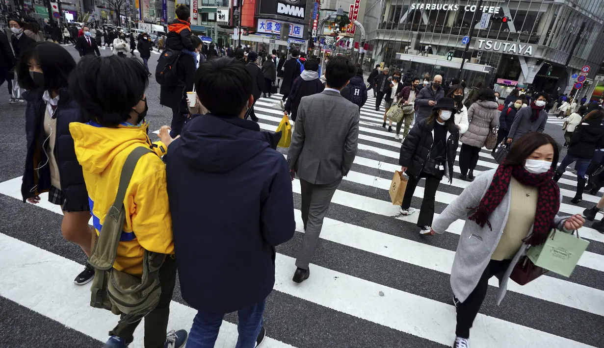 Orang-orang yang mengenakan masker berjalan di sepanjang penyeberangan pejalan kaki di daerah Shibuya, Tokyo, Selasa (5/1/2021). Ibu kota Jepang, Tokyo mengonfirmasi lebih dari 1.200 kasus virus corona COVID-19 baru pada Selasa (5/1). (AP Photo/Eugene Hoshiko)