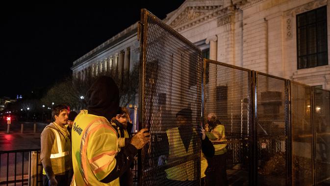 Pekerja memasang pagar besi di pintu masuk Gedung Putih mengantisipasi kerusuhan menjelang Pilpres Amerika Serikat di Washington DC, Senin (2/11/2020). Sebagai persiapan kemungkinan ada aksi terorisme atau protes massa, Gedung Putih membangun pagar baru. (Chris McGrath/Getty Images/AFP)