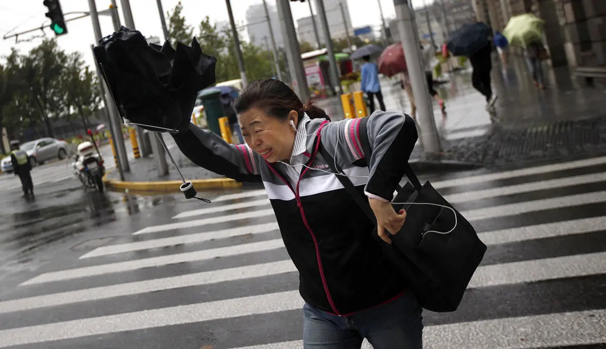 Seorang wanita menahan payung saat Topan Fung-Wong melintasi daerah dekat pesisir Shanghai, Tiongkok, (23/9/2014). (REUTERS/Carlos Barria)