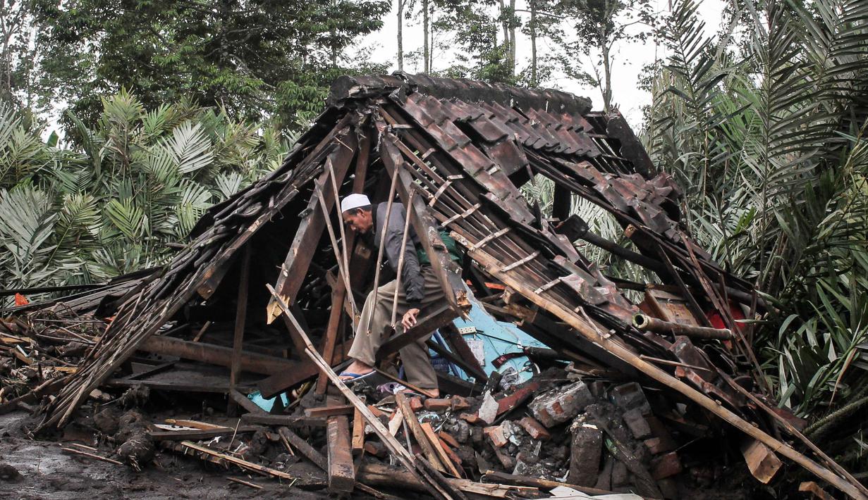 Badan Nasional Penanggulangan Bencana (BNPB) mengimbau masyarakat untuk tidak beraktivitas dalam radius 8 km dari puncak dan 20 km di sepanjang aliran Besuk Kobokan untuk menghindari korban jiwa. Tampak dalam foto, seorang pria mencari barang-barang yang bisa diselamatkan di dalam rumahnya yang hancur akibat aliran piroklastik selama letusan Gunung Semeru di Desa Supiturang, Lumajang, Jawa Timur pada Kamis 20 November 2025. (Agus Harianto/AFP)