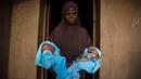 Seorang wanita muslim menggendong saudara laki-laki kembarnya yang berumur 4 hari di depan pintu rumahnya di Igbo Ora, Negara Bagian Oyo, Nigeria pada 3 April 2019.  Igbo Ora, sebuah wilayah di bagian barat daya Nigeria ini terkenal dengan anak-anaknya yang terlahir kembar. (REUTERS/Afolabi Sotunde)