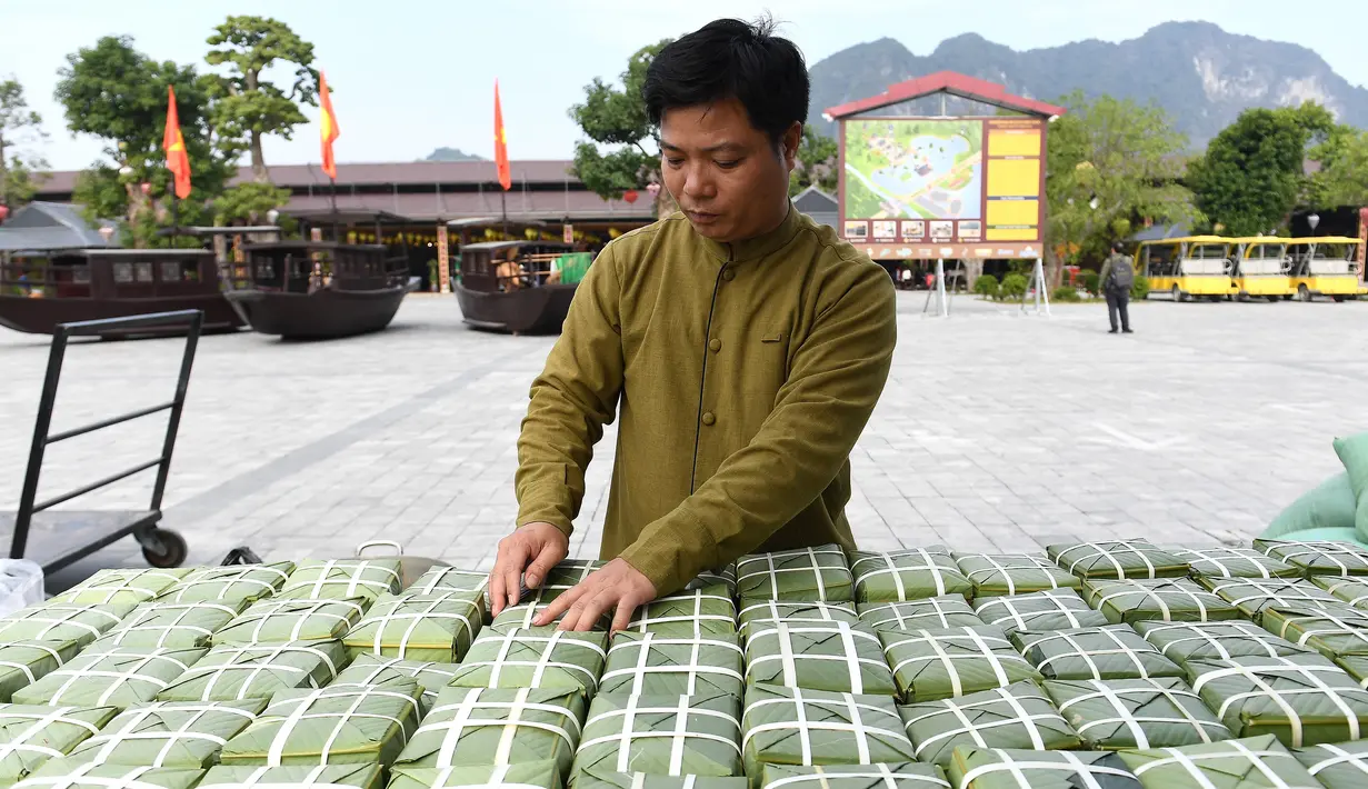 Seorang pria sedang mengatur paket "Banh Chung" atau kue beras tradisional Vietnam untuk amal, menjelang Tahun Baru Imlek atau festival Tet di Pagoda Tam Chuc di provinsi Ha Nam (7/1/2023). Banh Chung adalah kelezatan khas Vietnam yang terbuat dari ketan, daging babi, dan kacang hijau yang dibungkus dengan daun pisang dan dimasak selama 10 jam. (AFP/Nhac Nguyen)